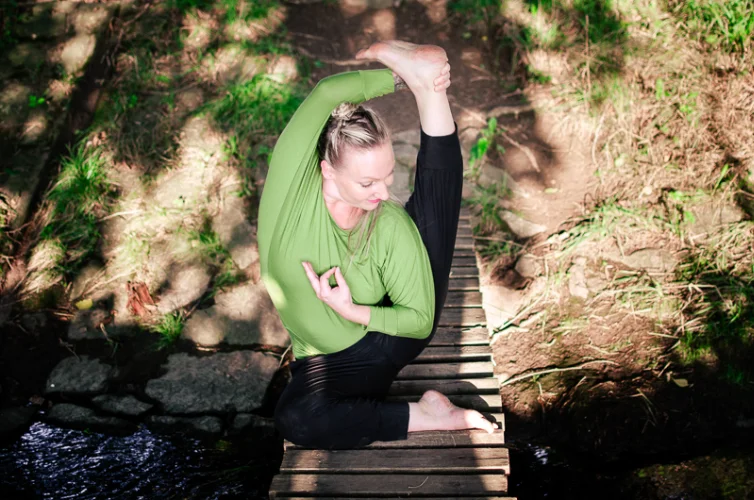 Portrét cvičitelky jógy v modrém triku na dřevěném mostě